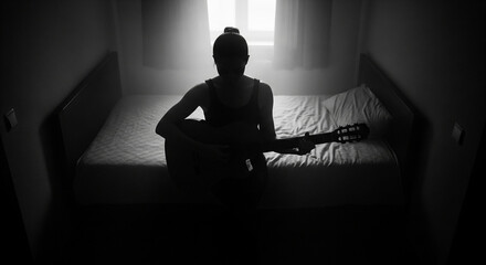 Silhouette of a Person Playing Guitar in a Dimly Lit Bedroom