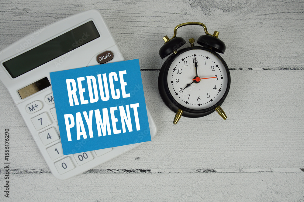 Aufkleber reduce payment text with calculator and alarm clock on wooden background