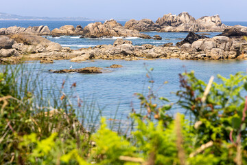 A beach with a rocky shoreline and a small path leading to the water. The water is calm and blue