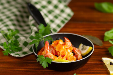 Culinary process of cooking shrimps in a frying pan with lemon on a wooden