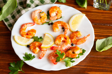 Delicious sea shrimps with lemon in a plate on a wooden