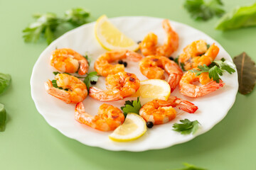 Hot shrimps with citrus slices and spices in a plate isolated on green
