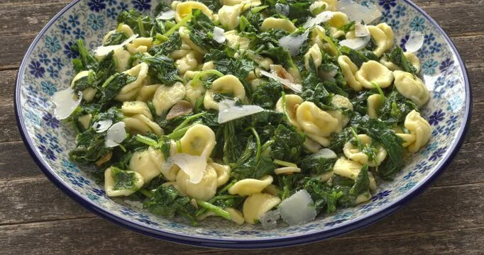 Orecchiette pasta with broccoli rabe (rapini) on a plate. South Italian dish. Rapini is a rich source of vitamin K.  Table spin. 
