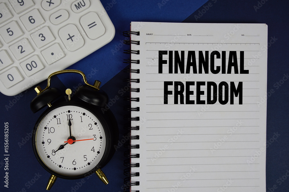 Poster financial freedom text written on notepad with calculator and alarm clock on navy blue background