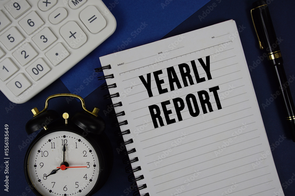 Poster yearly report text written on notepad with calculator and alarm clock on navy blue background