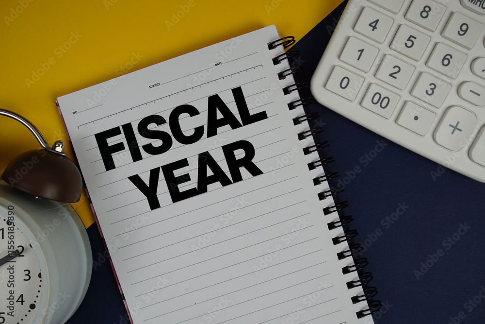 Poster fiscal year text written on notepad with calculator and alarm clock on navy blue background