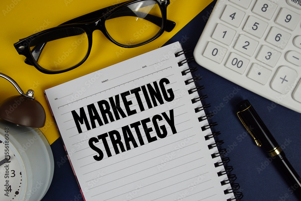 Poster marketing strategy text written on notepad with calculator and alarm clock on navy blue background