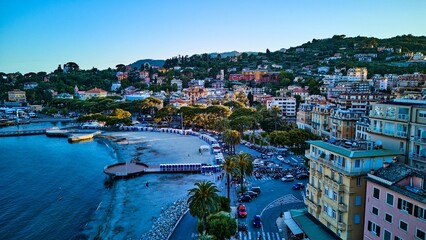 Aerial view of Rapallo sandy beach with summer bathing huts, palm-lined esplanade and colorful...