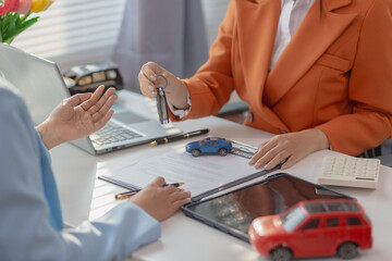 car dealer handing over keys female customer after successfully signing car sales contract. Concept...