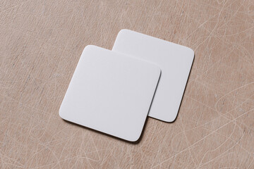 white blank square coaster on wood background for mockup template