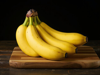 A bunch of ripe yellow bananas are resting on a wooden cutting board