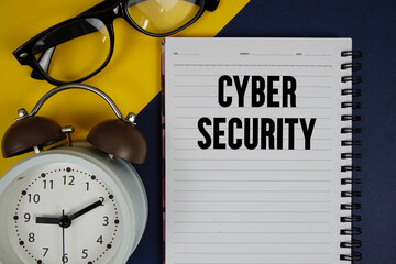 Cyber Security text written on notepad with alarm clock on blue background