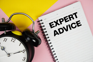 Expert Advice text written on notepad with alarm clock on pink background