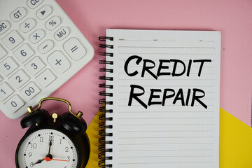 Credit Repair text written on notepad with calculator and alarm clock on pink background