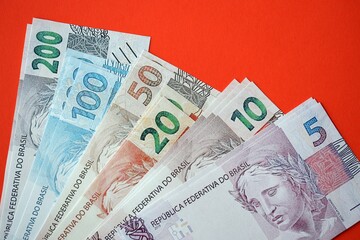 Close up of brazilian reais money bills in big amount on red. Pile of Brazil real currency banknotes