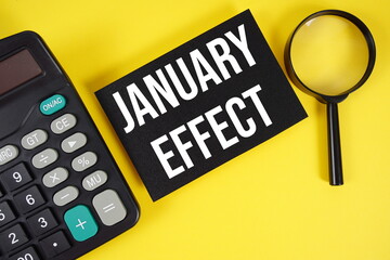 January Effect text with magnifying glass anc calculator on yellow background