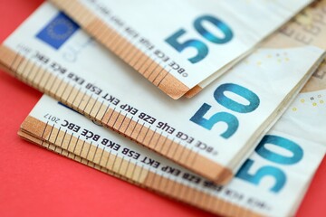 Big amount of european euro currency money notes on red color table close up