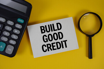 Build Good Credit text with magnifying glass anc calculator on yellow background