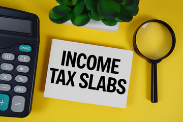 Income Tax Slabs text with magnifying glass anc calculator on yellow background