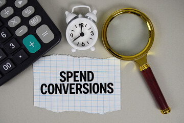 Spend Conversions text with alarm clock, magnifying glass anc calculator on gray background