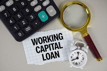 Working Capital Loan text with alarm clock, magnifying glass anc calculator on gray background