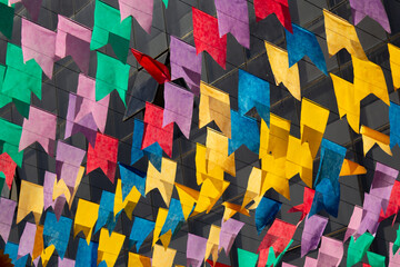 Bandeirinhas festivas, coloridas, penduradas ao ar livre dançando ao vento com janelas de um...
