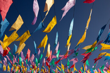 Bandeirinhas festivas penduradas ao ar livre dançando ao vento com fundo azul.