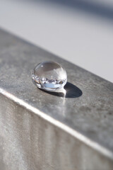 macro shot of isolated water droplet on polished iron surface focusing on smooth lines of light reflecting off
