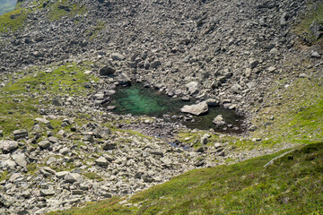 puddle or lake  with clear green colour in a boulder field high up in the mountains of montafon in Vorarlberg Austria