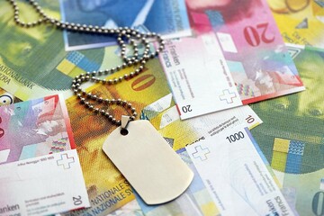 Swiss franc banknotes and military token. The current francs money bills and dogtags lies on table