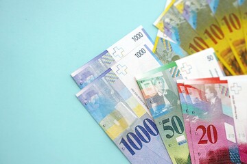 Swiss franc banknotes on blue background. The current francs money bills lies in big amount