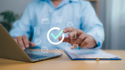 Person using a laptop with a large checkmark icon and business related icons calendar, graph,...