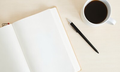 A minimalist flat lay of a white notebook, black pen, and coffee cup on a light wooden table with soft shadows.