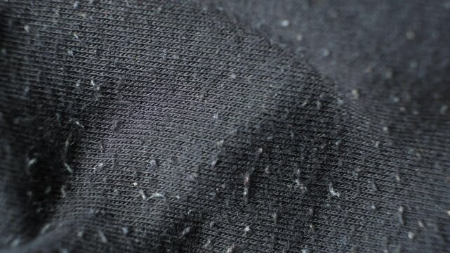Macro texture of gray fabric with lots of pilling and damage on the surface.