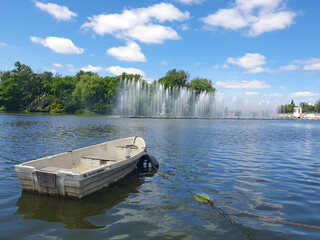 A boat on a river against the backdrop of an elegant fountain is an idyllic summer landscape filled...