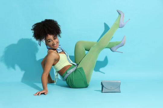 Fashionable portrait of beautiful Brazilian woman in stylish outfit on light blue background