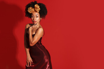 Fototapeta premium Fashionable portrait of beautiful Brazilian woman in stylish outfit on red background. Space for text