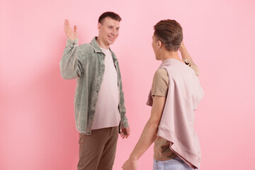 Friends welcoming each other on pink background