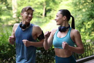 Fototapeta premium Sporty couple with headphones running in park