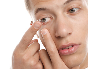 Man putting in contact lens on white background, closeup