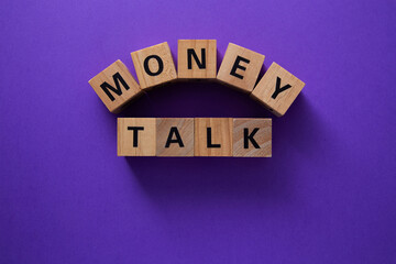 Money talk composed with wooden cubes on purple background