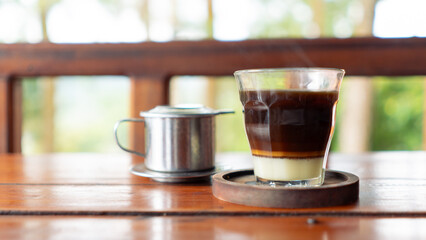 Vienna Coffee or Vietnam Drip with sweet condensed milk on wooden table. Vietnamese traditional drip filter coffee.