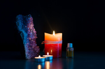 imagen con un ambiente íntimo y místico que incluye velas encendidas, una piedra amatista y...