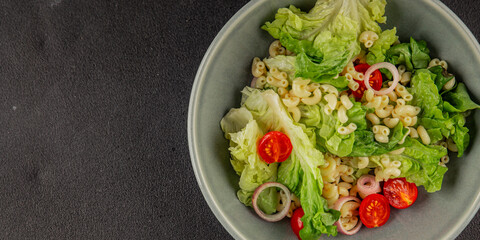 Pasta salad green leaf lettuce, tomato, pasta, onion fresh delicious gourmet food background on the table rustic food top view copy space keto and paleo diet vegan and vegetarian food