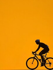 Obraz premium A cyclist in a helmet and athletic gear pedals gracefully against an orange backdrop, creating a dynamic silhouette on the road.