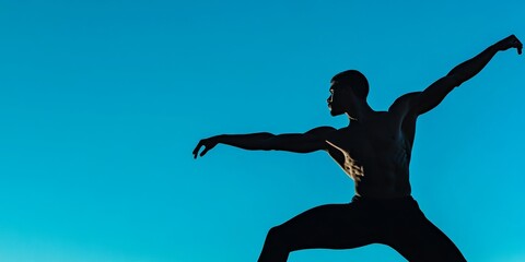 The silhouetted man in a dynamic yoga pose stretches gracefully against a serene blue sky, embodying balance and flexibility.