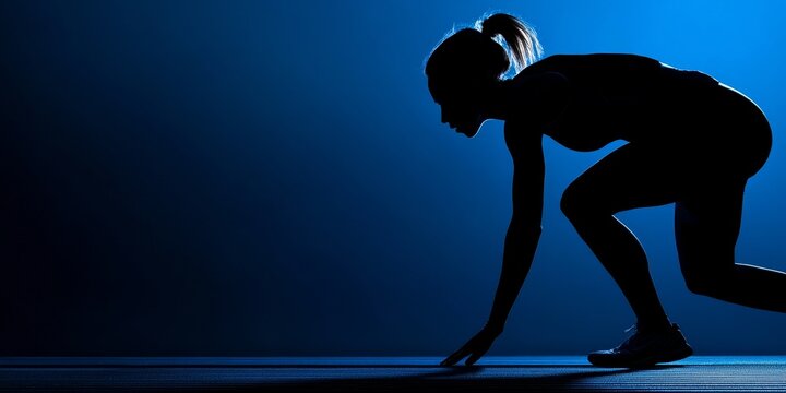 The intense runner in a crouched position, poised for an explosive start with focused determination and athletic form against a vivid blue backdrop.