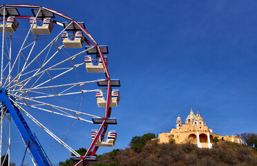 Ferris wheel with Cholula pyramid church in background