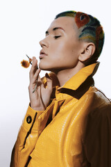 woman with colorful shaved hairstyle wearing a vibrant yellow leather jacket, posing thoughtfully...