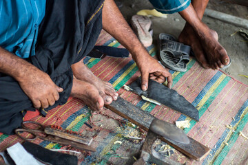 Two cobblers take a large piece of leather to sew shoes